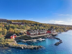 A waterfront property with a dock, boats, and a large red building with multiple windows and balconies.