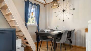 Een eetruimte met een tafel gedekt voor vier personen, een houten trap en een moderne lamp.