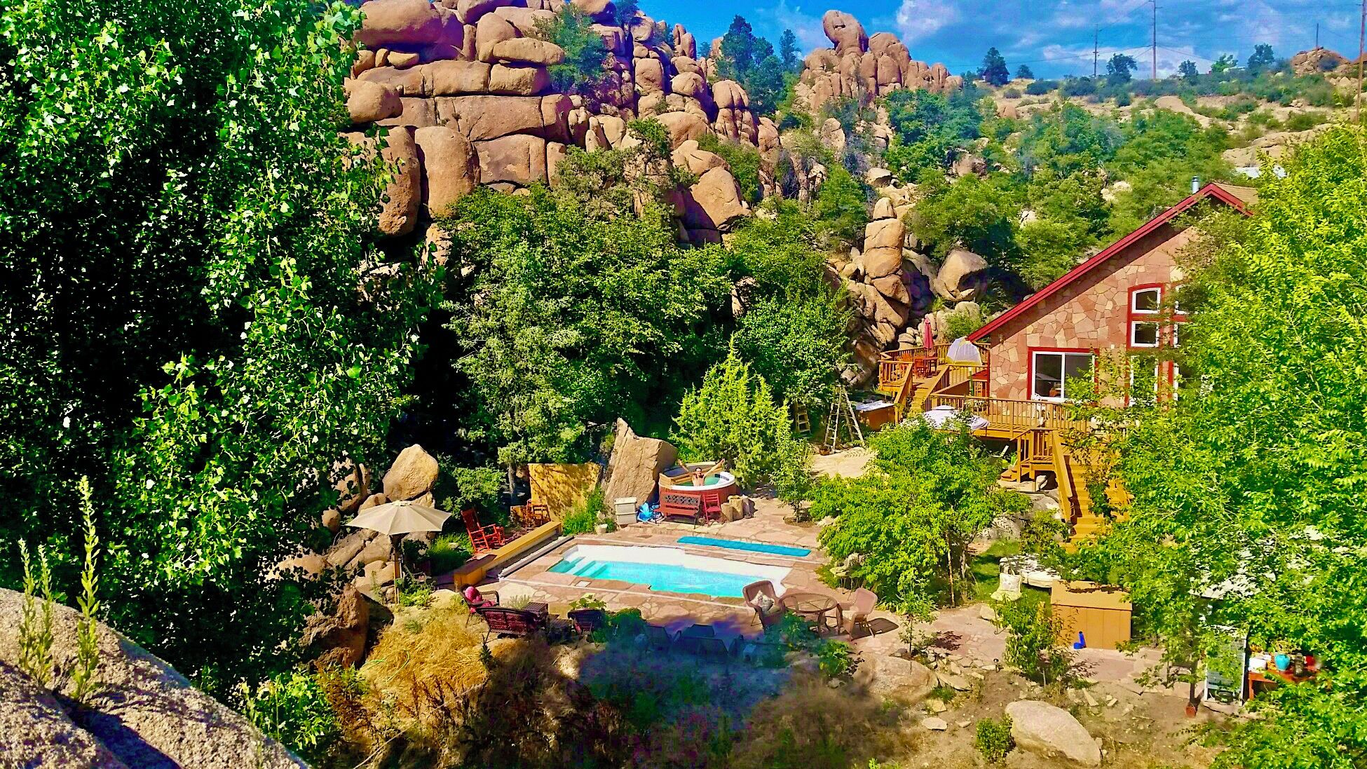 Un resort con piscina, mobiliario exterior y vistas a montañas escarpadas.