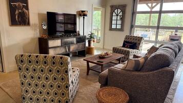 A living room with a sofa, armchair, and a television.