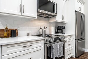 Une cuisine moderne avec des meubles blancs, des appareils en acier inoxydable et un four encastré.