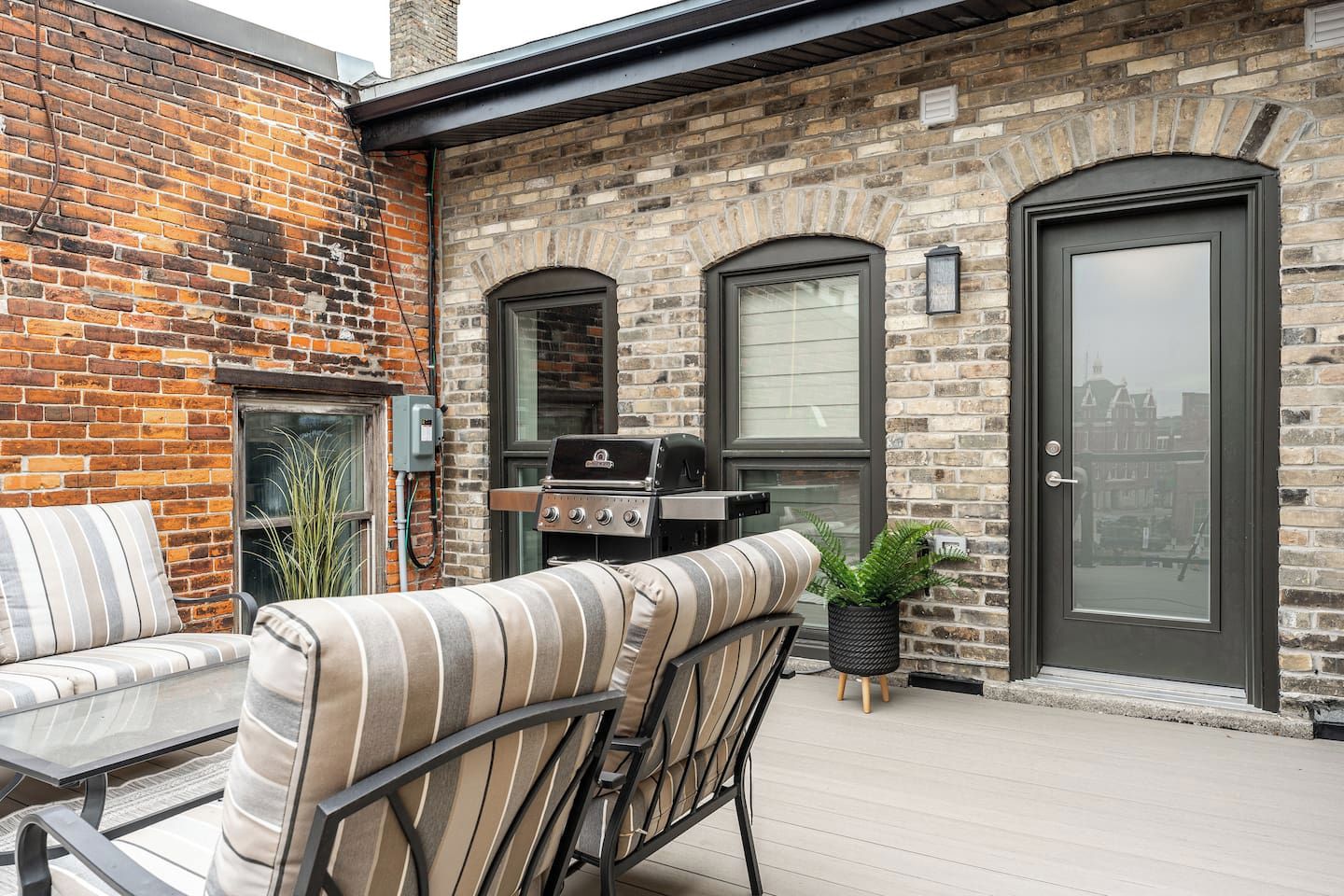 A patio with a grill, outdoor seating, and a brick wall.