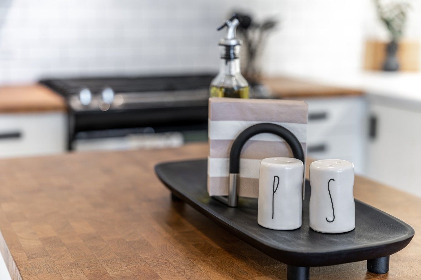A kitchen counter with a black tray holding two white mugs and a decorative item.