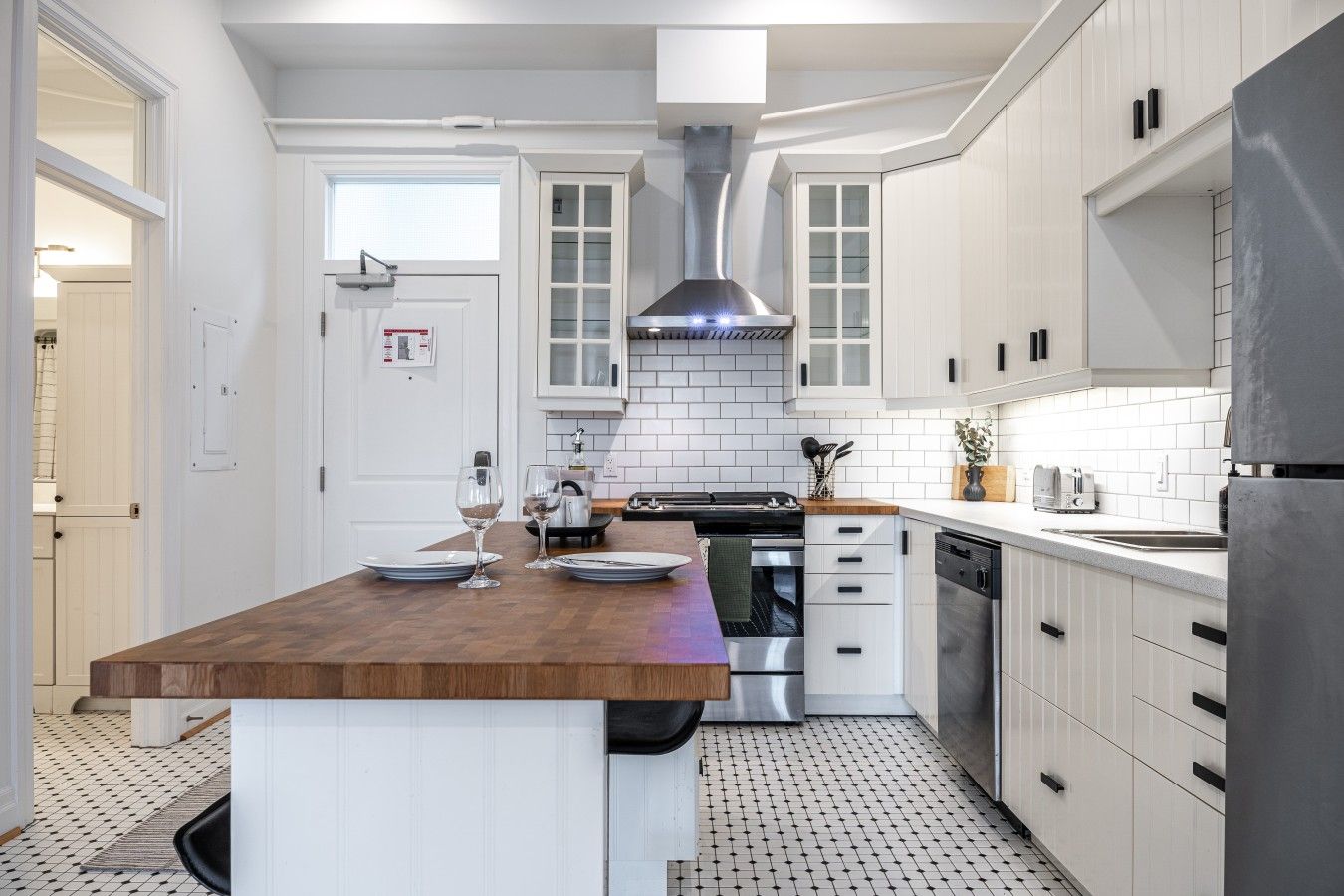 A modern kitchen with white cabinetry, a central island, stainless steel appliances, and a patterned floor.