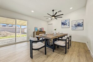 A dining area with a large table, chairs, a ceiling fan, and artwork on the walls. - 4BR - Near Stadium - Arcade - Pool Table - Parking (Phoenix)
