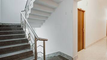 A staircase with metal railings leading to a landing, a wooden door, and a tiled floor.