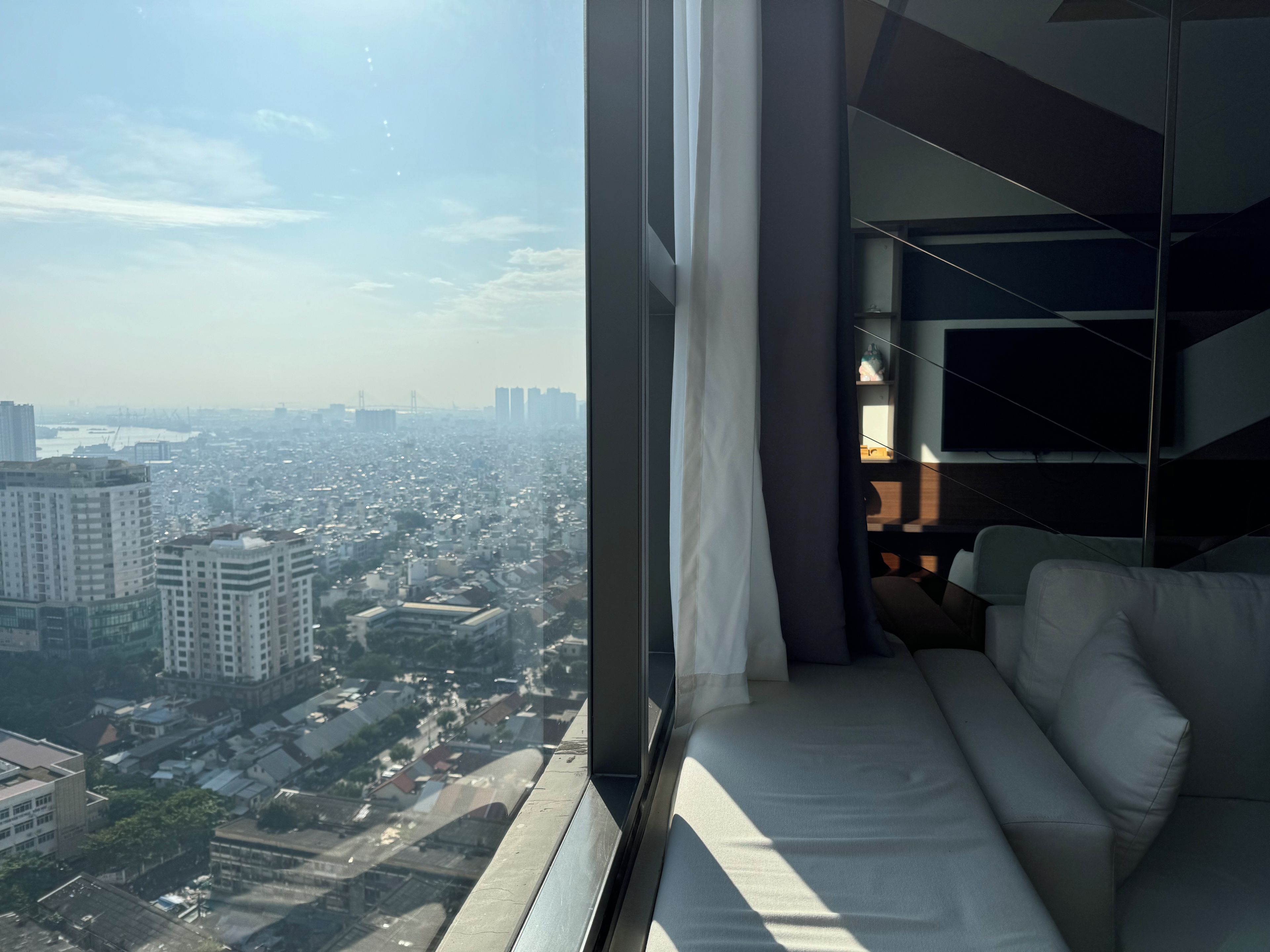 Un interior de edificio alto con vista a la ciudad, un sofá y un diseño moderno.