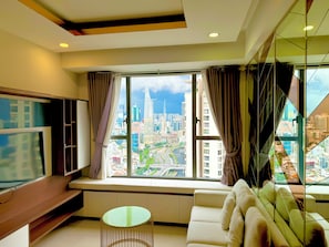 A modern living room with a large window, a flat-screen TV, a sofa, and a small round table. - River gate apartment  (Khanh Hoi)