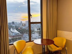 Una habitación con un ventanal grande, dos sillas amarillas y una mesa redonda pequeña.