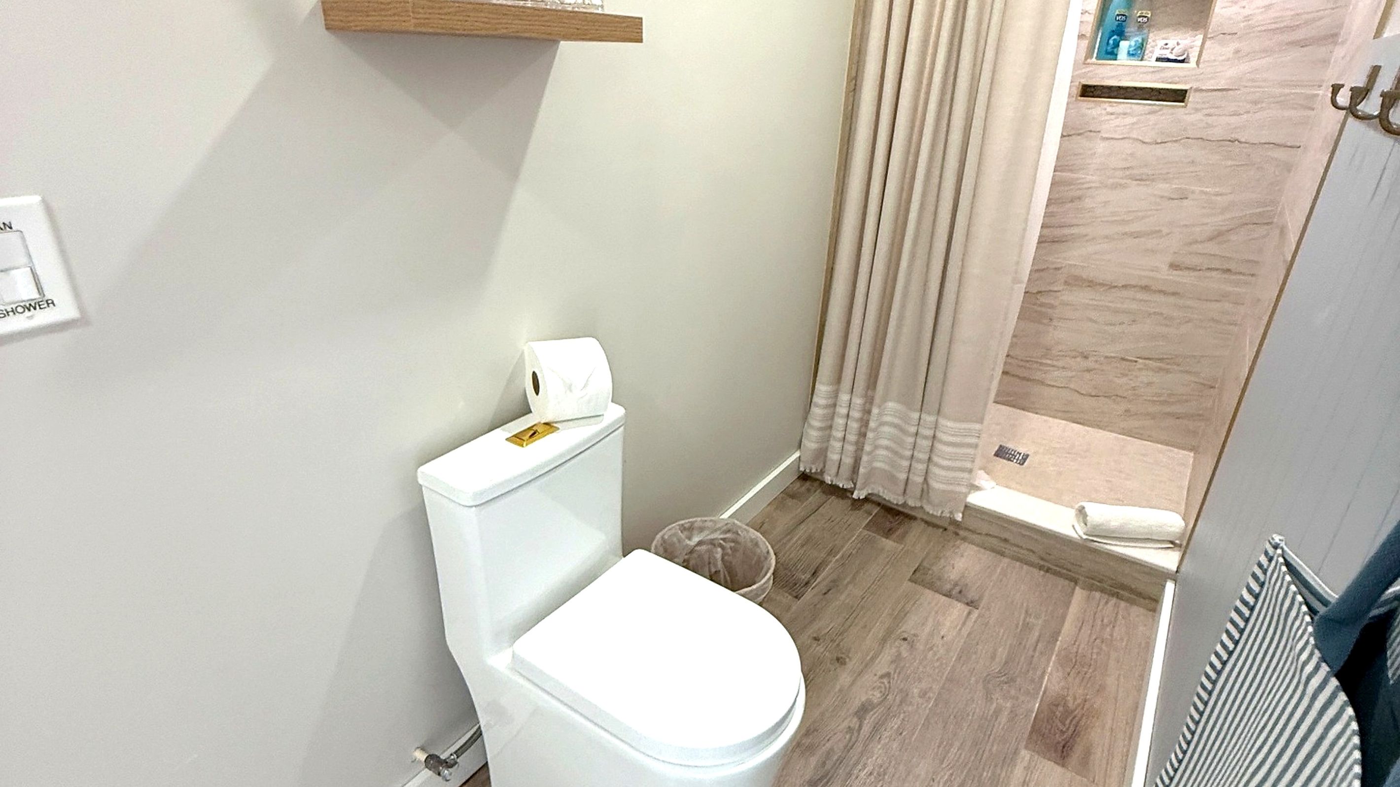 A small bathroom with a toilet, a shower, and a towel rack.
