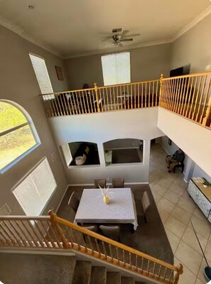 A multi-level interior with a dining area, staircase, and a balcony with a railing. - Vegas oasis,  central location, spacious 4 bd 3 bath,  pool & jacuzzi. (North Las Vegas)