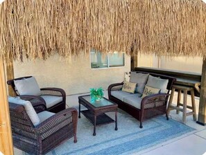 An outdoor seating area with wicker furniture and a thatched roof. - Vegas oasis,  central location, spacious 4 bd 3 bath,  pool & jacuzzi. (North Las Vegas)