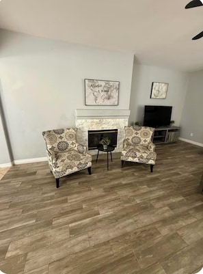 A living room with two patterned armchairs, a fireplace, and a television. - Vegas oasis,  central location, spacious 4 bd 3 bath,  pool & jacuzzi. (North Las Vegas)