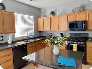A kitchen with wooden cabinets, a granite countertop, a stove, a microwave, and a sink. - Vegas oasis,  central location, spacious 4 bd 3 bath,  pool & jacuzzi. (North Las Vegas)