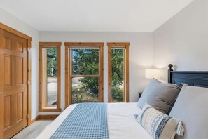 A bedroom with a bed, a nightstand, and a window with a view of greenery. - Wonderful 3-bedroom house in Silverthorne perfect for your getaway (Silverthorne)
