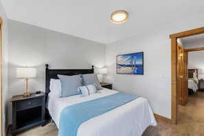 Une chambre d’hôtel avec un lit, des tables de chevet, un tableau et une porte en bois.