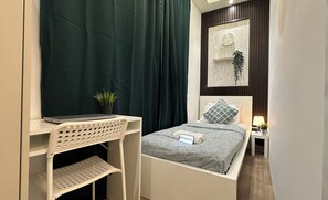 A bedroom with a bed, a desk, a chair, a potted plant, and a wall clock. - Wanderlust Partition Room in Barsha (Dubai)