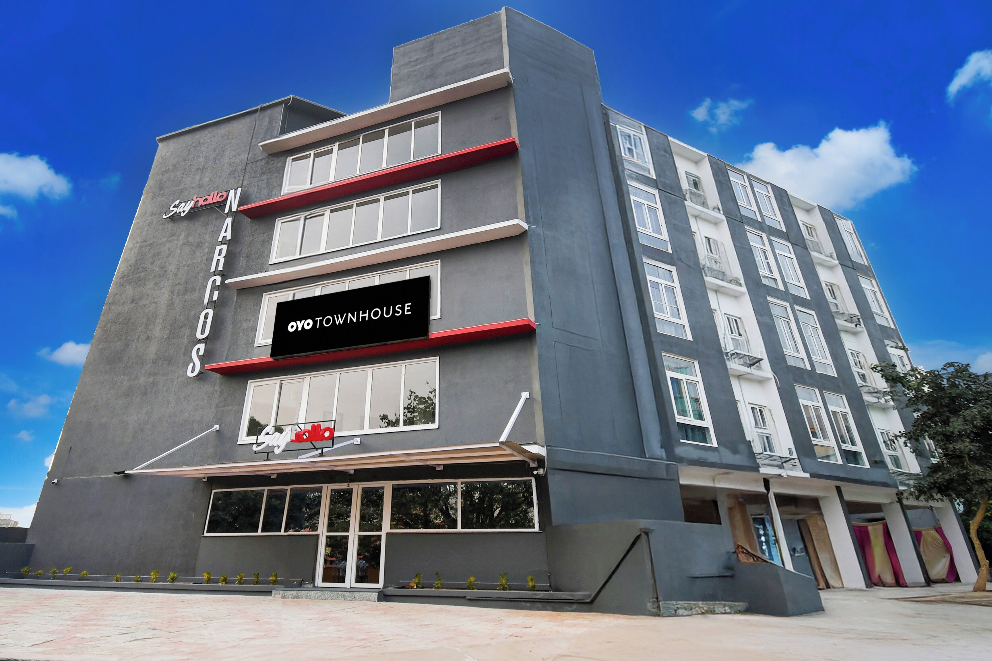 A multi-story building with a prominent sign for 'OYO DOWNHOUSE' and a smaller sign for 'Say hello NARCOS'.
