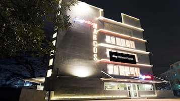 Ein mehrstöckiges Gebäude mit beleuchteter Beschilderung, darunter 'NARCO' und 'OYO TOWNHOUSE' an der Fassade.