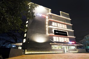 Un edificio de varios pisos con señalización iluminada, incluyendo 'NARCO' y 'OYO TOWNHOUSE' en la fachada.