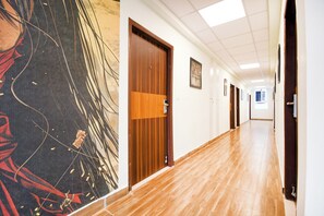 A hallway with wooden doors, a tiled floor, and a wall with a large abstract painting. - Townhouse Sayhallo Narcos (Bhubaneshwar)
