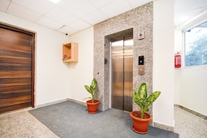 Un ascensor amb acabat metàl·lic, una porta de fusta i una petita estant amb objectes.