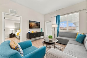 A modern living room with a sofa, armchairs, a coffee table, and a TV. - Spacious 3BR condo, Perfect Orlando Home Base (Orlando)