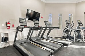 A gym with treadmills, a television mounted on the wall, and a fire extinguisher on the wall. - Spacious 3BR, Near Parks and Convention Center (Orlando)
