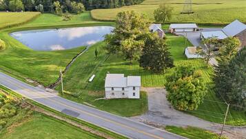 A rural landscape with a pond, a road, and a house with a garage.