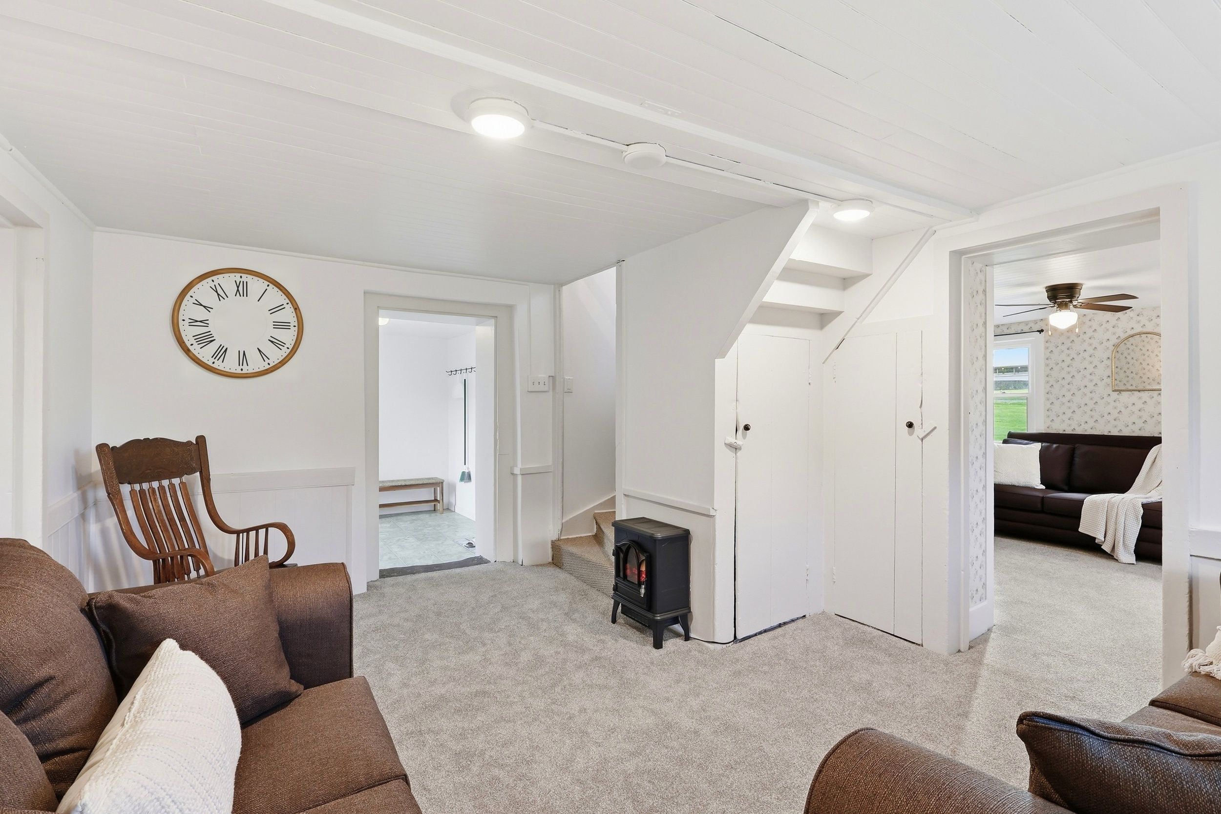 Un vaste espace de vie agrémenté d’une grande horloge, d’une cheminée et d’un coin salon confortable.