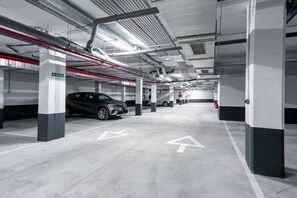 A multi-level parking garage with clear directional arrows on the floor, fire extinguishers, and a 'SALIDA' sign indicating an exit. - Sea Blue Torrox Costa by Casasol (Torrox)