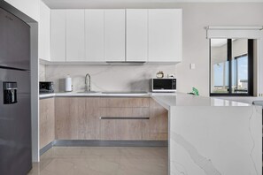 A modern kitchen with a built-in refrigerator, a coffee machine, and a microwave. - Distrito Corazón: Bright 1BR w/ Balcony & Pool (Playa del Carmen)