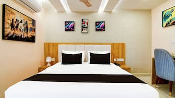 Quarto de hotel com uma cama grande, um ventilador de teto e três obras de arte penduradas na parede.
