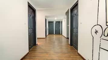 Un corridoio con pavimento in legno, pareti bianche e porte su entrambi i lati.