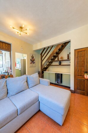 A living room with a sectional sofa, a staircase, and a kitchen area. - Villa 13 Jarabacoa with AC/ Wifi Jacuzzi (Jarabacoa)