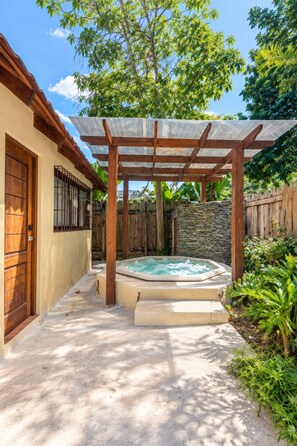 Ein Garten mit Whirlpool, einer Holzpergola und einer Steinmauer.