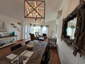 A spacious living area with a wooden dining table, a chandelier, and a large mirror on the wall. - Li Conchi Villa 17 - detached villa within the Li Conchi Village (Castiadas)