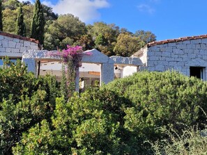 A stone building with a white facade, surrounded by dense greenery and trees. - Li Conchi Villa 17 - detached villa within the Li Conchi Village (Castiadas)