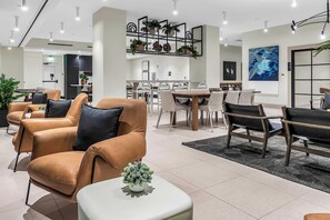 A modern living room with leather sofas, a dining area with a wooden table, and a kitchen in the background. - The Metro Miami Retreat, Parking & Amenities (Miami)