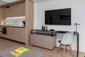 Eine moderne Küche mit Einbauofen, Kaffeemaschine und einem flachbildfernseher an der Wand.