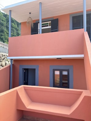 Een gebouw met twee verdiepingen, een plat dak en een balkon.