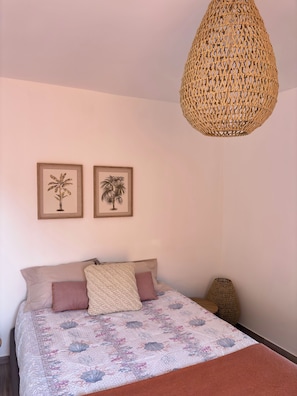 A bedroom with a bed, two framed pictures, a woven hanging light fixture, and a small woven stool. - Casa do Portinho - Country house with a spectacular view of the Atlantic Ocean (Ponta Delgada)