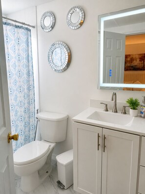 Ein Badezimmer mit Toilette, Waschbecken und drei Spiegeln an der Wand.
