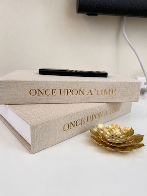 Zwei Bücher mit dem Titel 'ONCE UPON A TIME', obenauf ein Stift und daneben eine dekorative goldene Lotusblume.