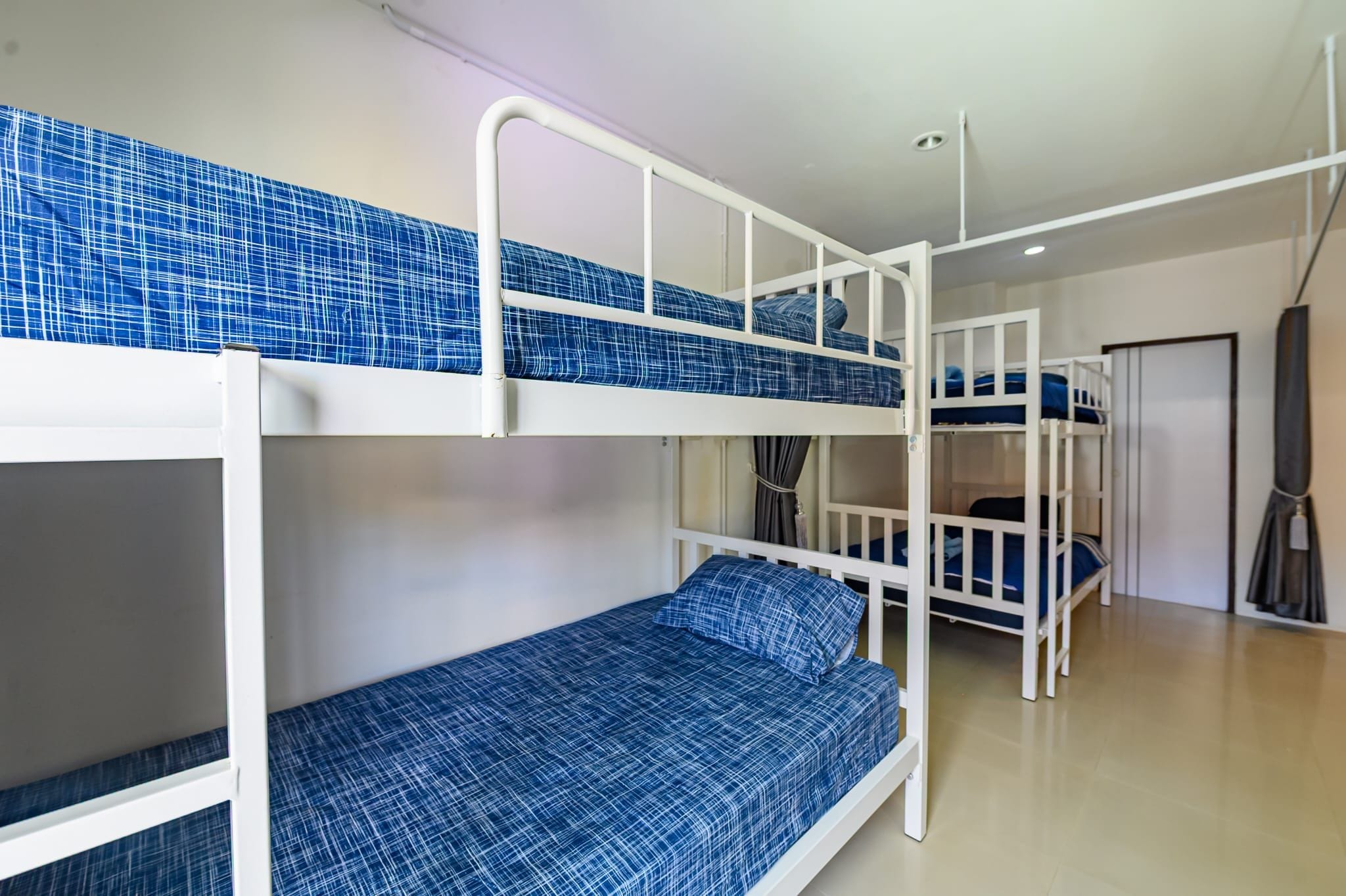 A bunk bed room with a white rail and blue bedding.
