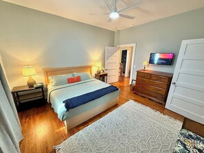 A bedroom with a bed, bedside tables, a dresser, a television, and a ceiling fan. - Charming updated home w/large bedrooms & big deck. Great for groups & families! (Shelbyville)