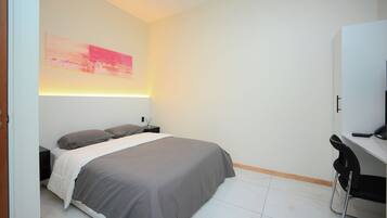 A modern bedroom with a bed, bedside table, and a desk with a chair.