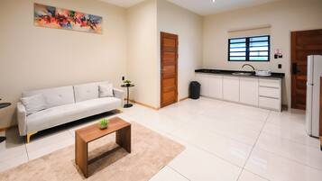 A modern living room with a sofa, a coffee table, and a painting on the wall.