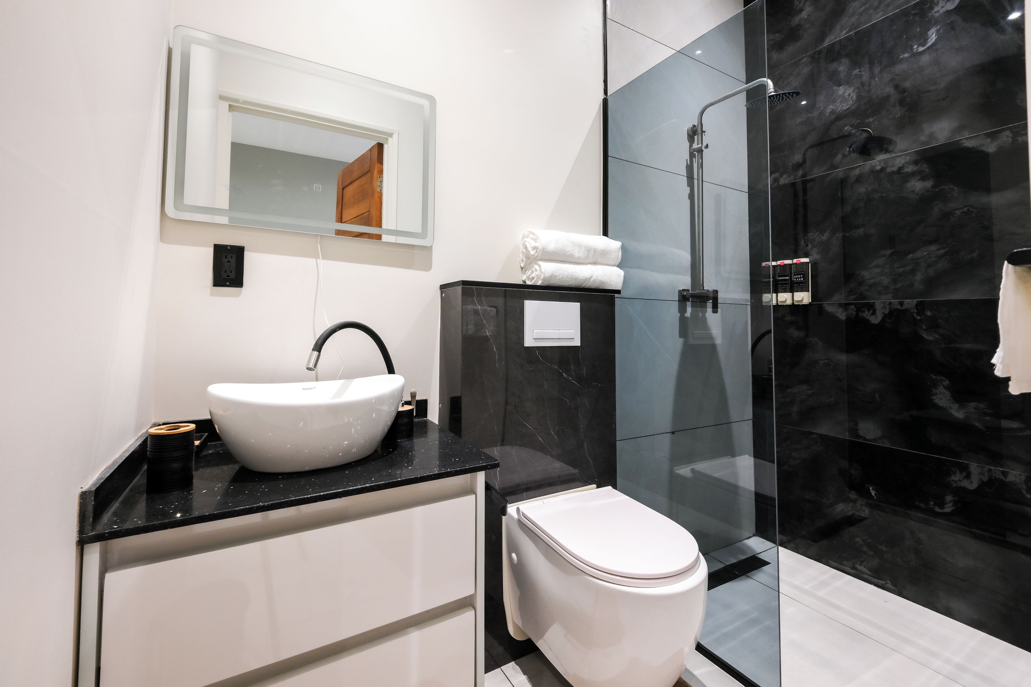 A modern bathroom with a white sink, a toilet, and a glass-enclosed shower.