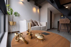 A modern living room with a round wooden coffee table, a white sofa, and a plant. - Luxury Duplex with City Views (Medellín)